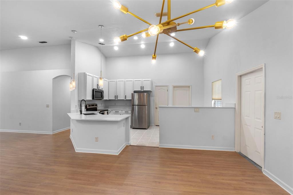 A kitchen with white cabinets, stainless steel appliances, and a breakfast bar under a chandelier — 287 MARSH LANDING CIRCLE, DEBARY, FL