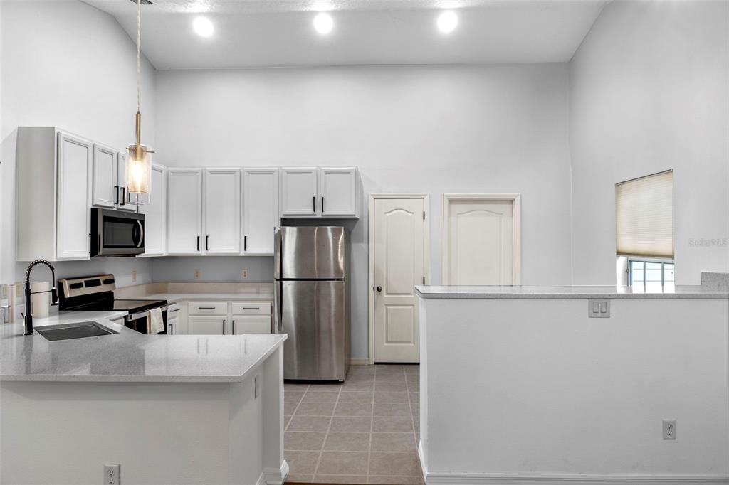 A kitchen features white cabinets, stainless steel appliances, and a peninsula with a sink — 287 MARSH LANDING CIRCLE, DEBARY, FL