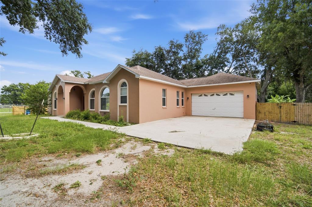 A single-story peach-colored house with a two-car garage and a concrete driveway — 6611 W KNIGHTS GRIFFIN ROAD, PLANT CITY, FL