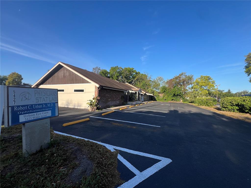 A single-story commercial building with a parking lot and a prominent sign in the foreground — 5427 WATER STREET, NEW PORT RICHEY, FL