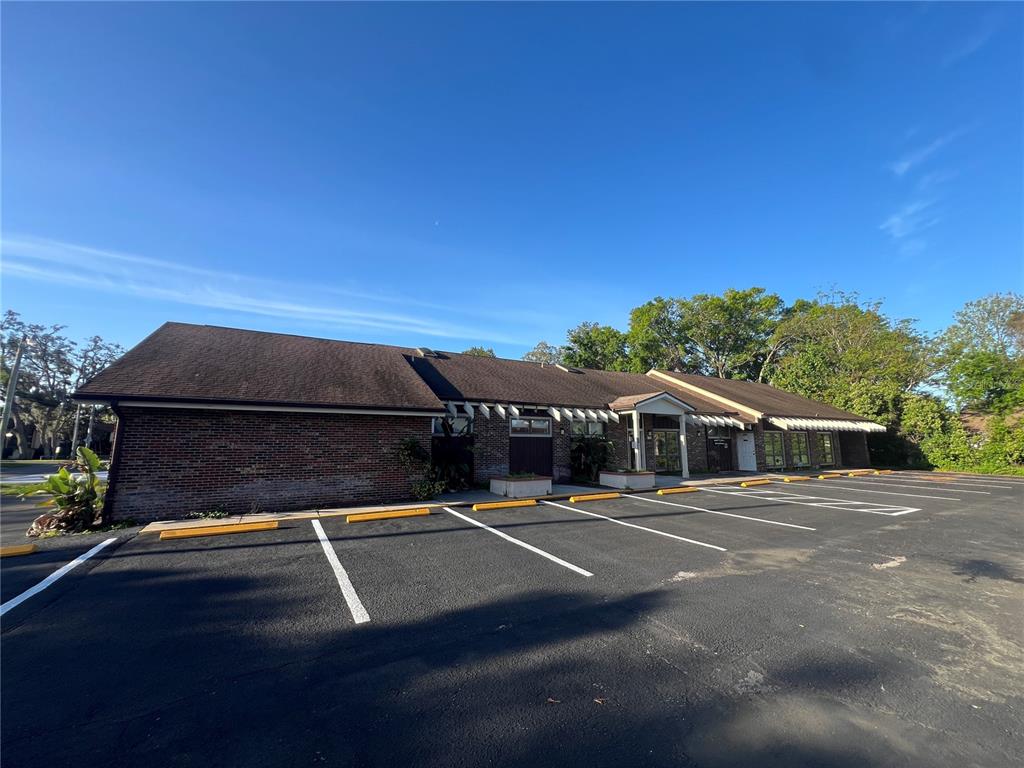 A single-story brick commercial building with a shingled roof and an adjacent asphalt parking lot — 5427 WATER STREET, NEW PORT RICHEY, FL