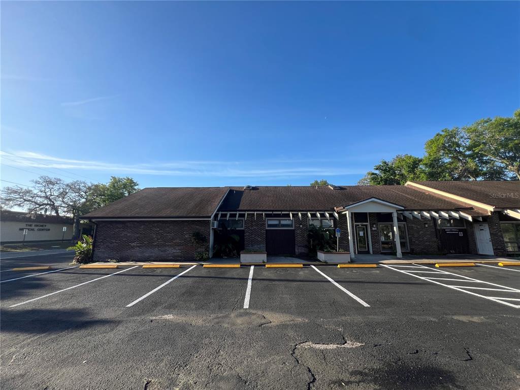 A single-story brick commercial building features a dark shingled roof and a paved parking lot — 5427 WATER STREET, NEW PORT RICHEY, FL