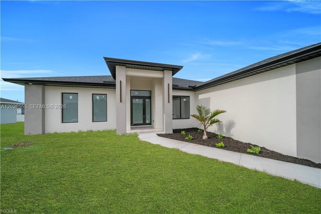 The exterior of a modern single-story house features a covered entryway and a landscaped yard — 2507 39th ST SW, Lehigh Acres FL 33976, LEHIGH ACRES, FL