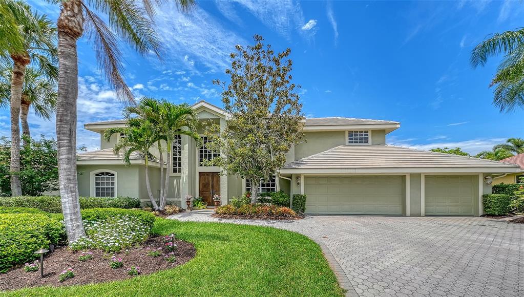 A two-story house with a light green exterior, a paved driveway, and palm trees — 4839 SWEETMEADOW CIRCLE, SARASOTA, FL