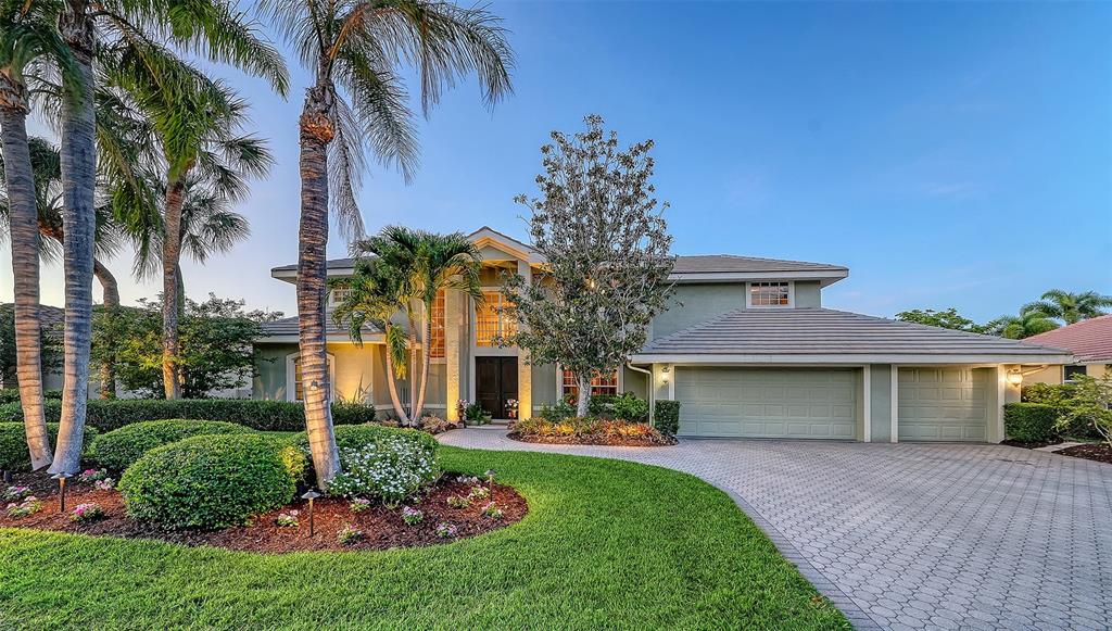 A two-story house with a paved driveway, palm trees, and a three-car garage — 4839 SWEETMEADOW CIRCLE, SARASOTA, FL