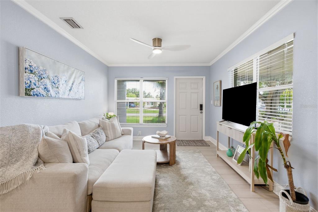 A living room features a light-colored sectional sofa, a television on a console, and windows — 2918 W ELLIS DRIVE, TAMPA, FL