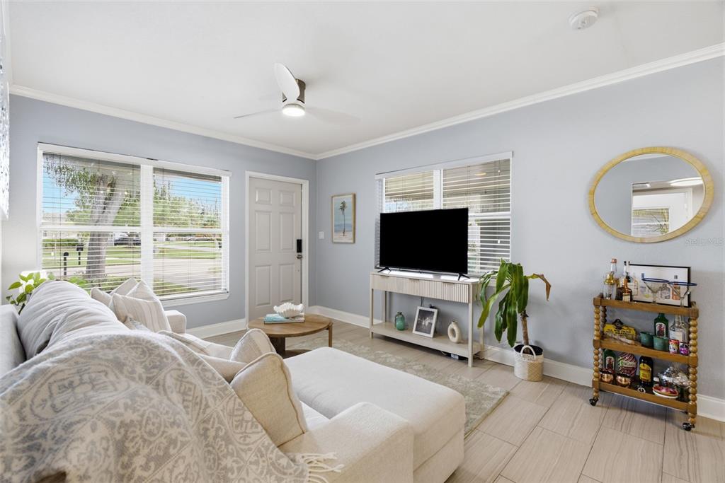A living room features a light-colored sectional sofa, a television on a console, and a bar cart — 2918 W ELLIS DRIVE, TAMPA, FL