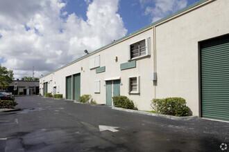 A low-rise commercial building with a parking lot, green roll-up doors, and small windows — 1791 Blount Road # 814, Pompano Beach FL 33069, POMPANO BEACH, FL
