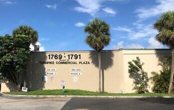 The exterior of a beige commercial plaza building features palm trees and signage on the wall — 1791 Blount Road # 814, Pompano Beach FL 33069, POMPANO BEACH, FL