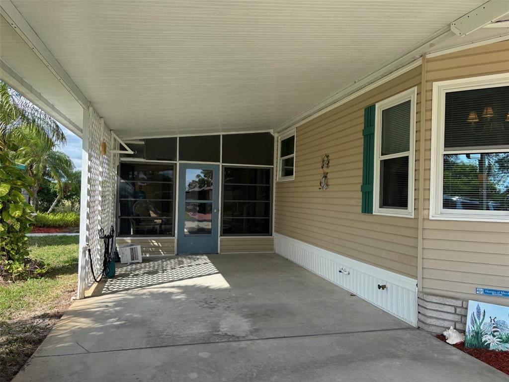 A concrete carport area leads to a screened-in porch with a blue door and siding — 6107 GRAND OAKS DRIVE SE, WINTER HAVEN, FL