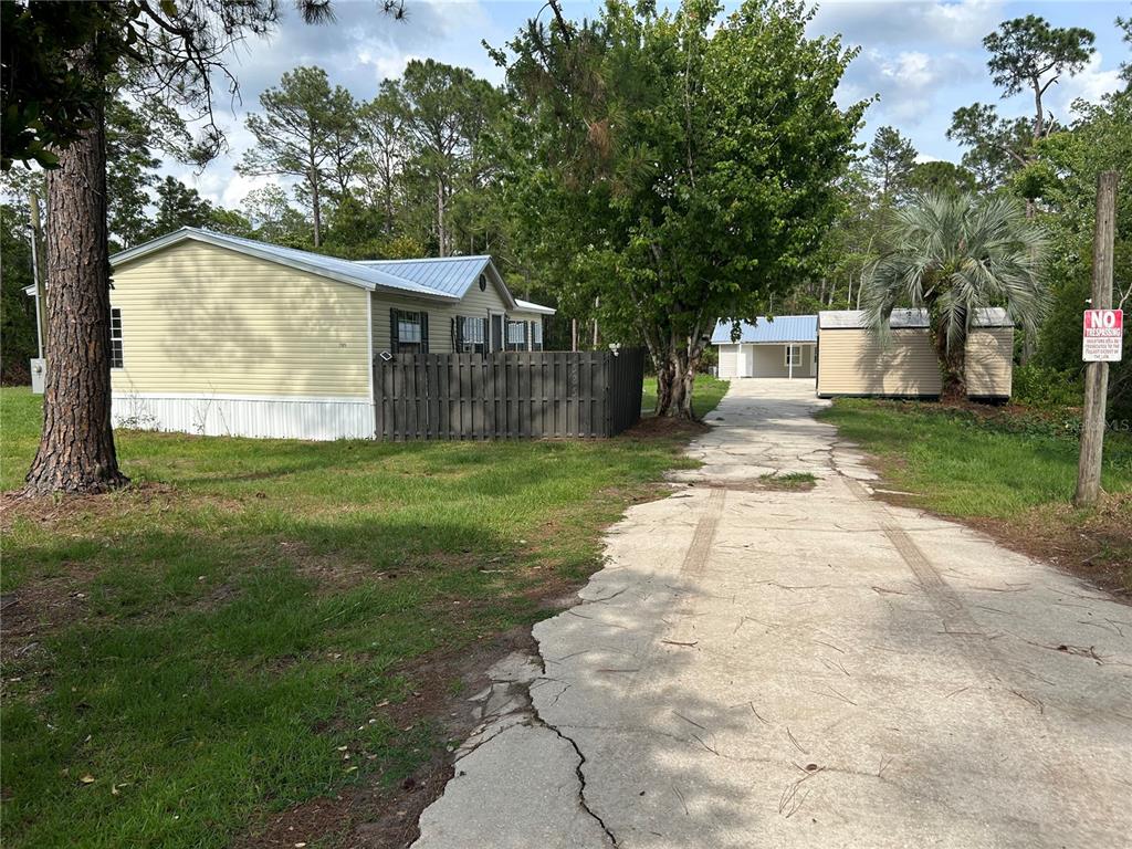 A yellow mobile home with a fenced yard and a long concrete driveway — 2585 VISTA PARK DRIVE, DELAND, FL