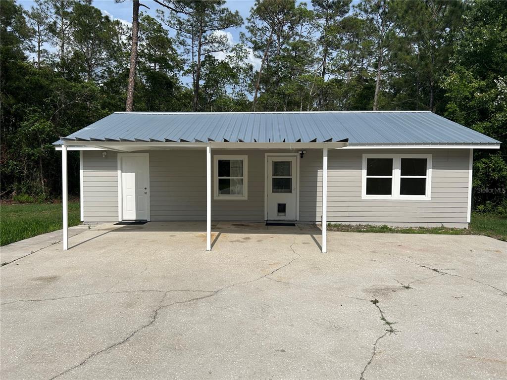 A single-story house with gray siding, a metal roof, and a concrete driveway — 2585 VISTA PARK DRIVE, DELAND, FL