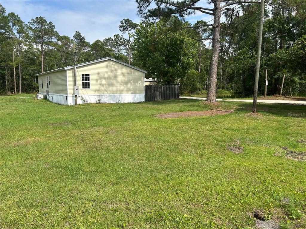 A light-colored mobile home sits on a grassy lot surrounded by trees — 2585 VISTA PARK DRIVE, DELAND, FL