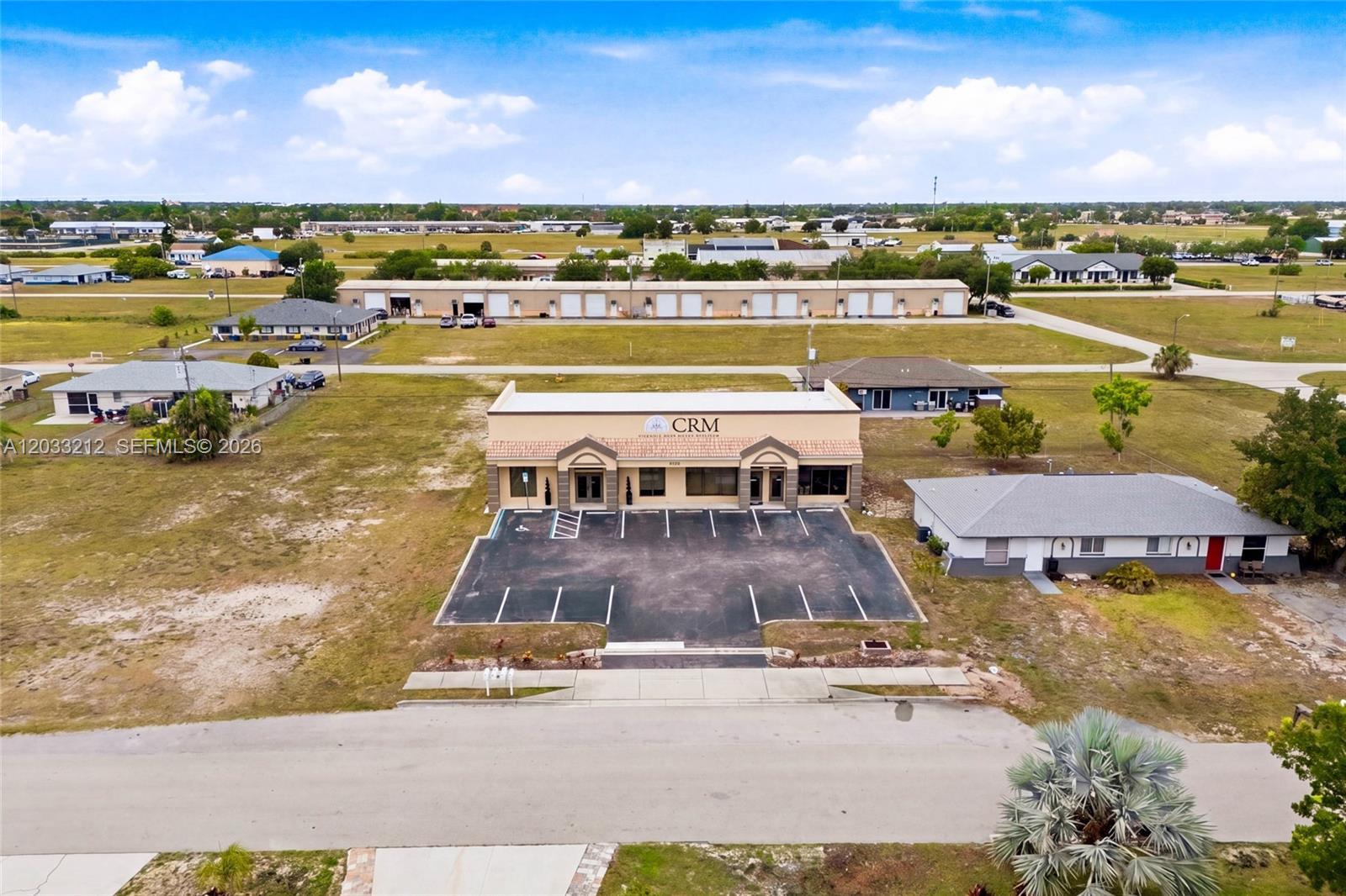 An aerial view shows a commercial building with a parking lot surrounded by open land — CAPE CORAL, FL