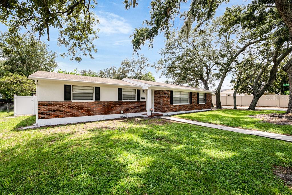 A single-story house with a brick and white exterior sits on a grassy lot — 1924 W NORTH STREET, TAMPA, FL