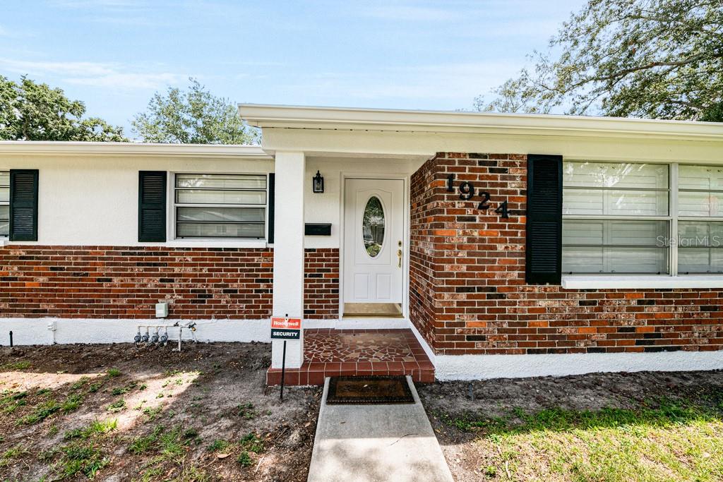 The exterior of a single-story home features a brick facade, white trim, and a front door — 1924 W NORTH STREET, TAMPA, FL
