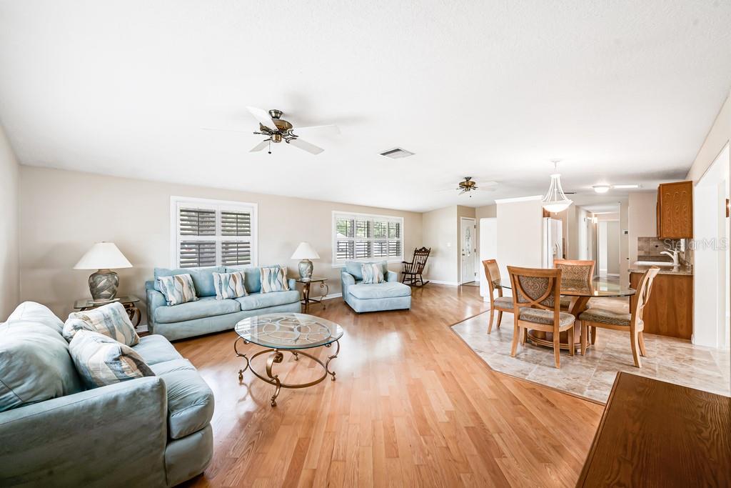 An open-concept living and dining area features light wood flooring, blue sofas, and tile flooring — 1924 W NORTH STREET, TAMPA, FL