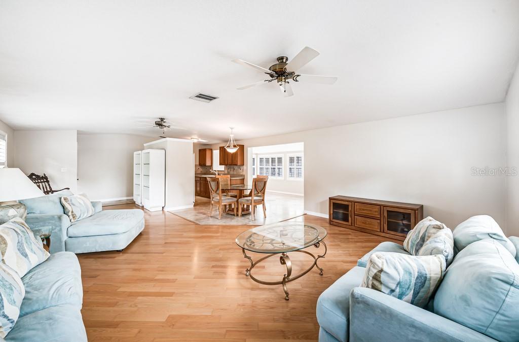 An open-concept living area features light wood flooring, light blue sofas, and a dining nook — 1924 W NORTH STREET, TAMPA, FL
