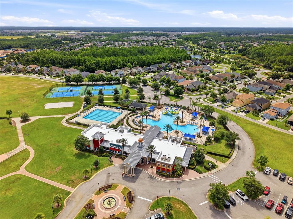 An aerial view of a community clubhouse featuring a swimming pool, tennis courts, and parking — 8948 FLOURISH DRIVE, LAND O LAKES, FL