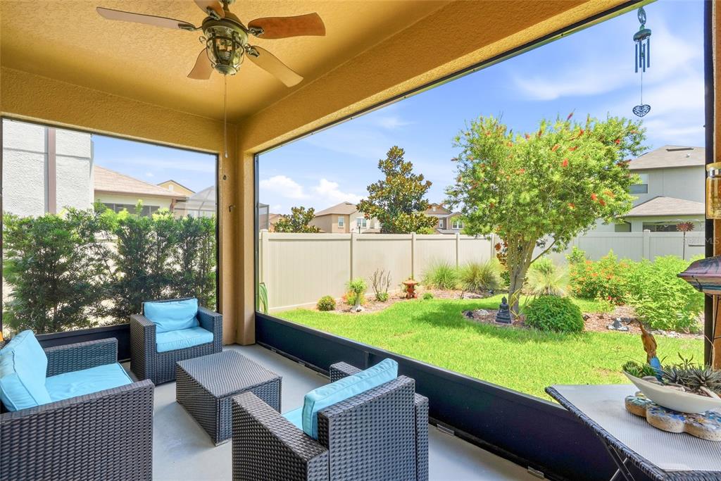 A screened-in patio features wicker furniture, a ceiling fan, and a view of the backyard — 8948 FLOURISH DRIVE, LAND O LAKES, FL