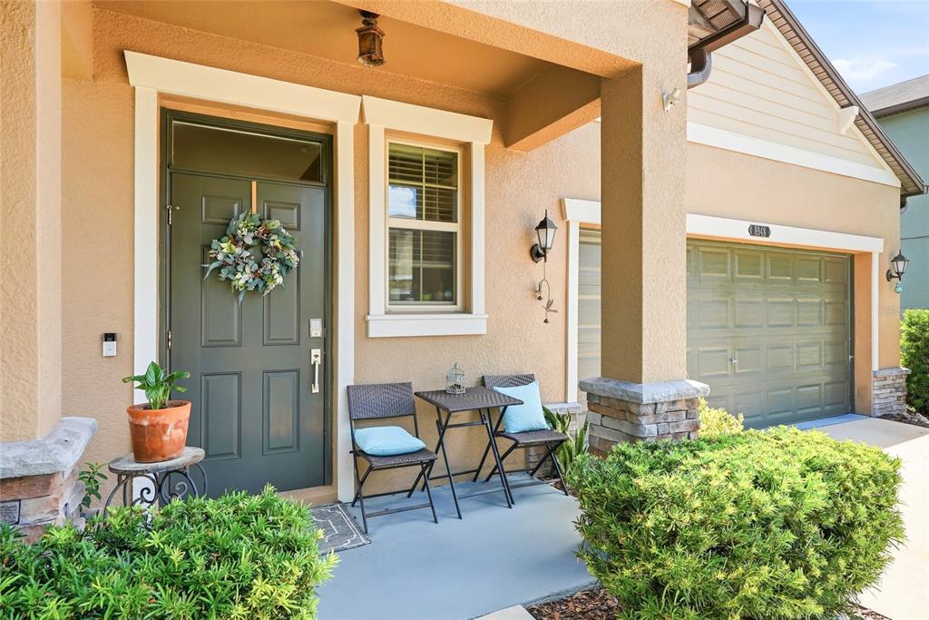 A front porch features a dark green door, a small bistro set, and a garage — 8948 FLOURISH DRIVE, LAND O LAKES, FL