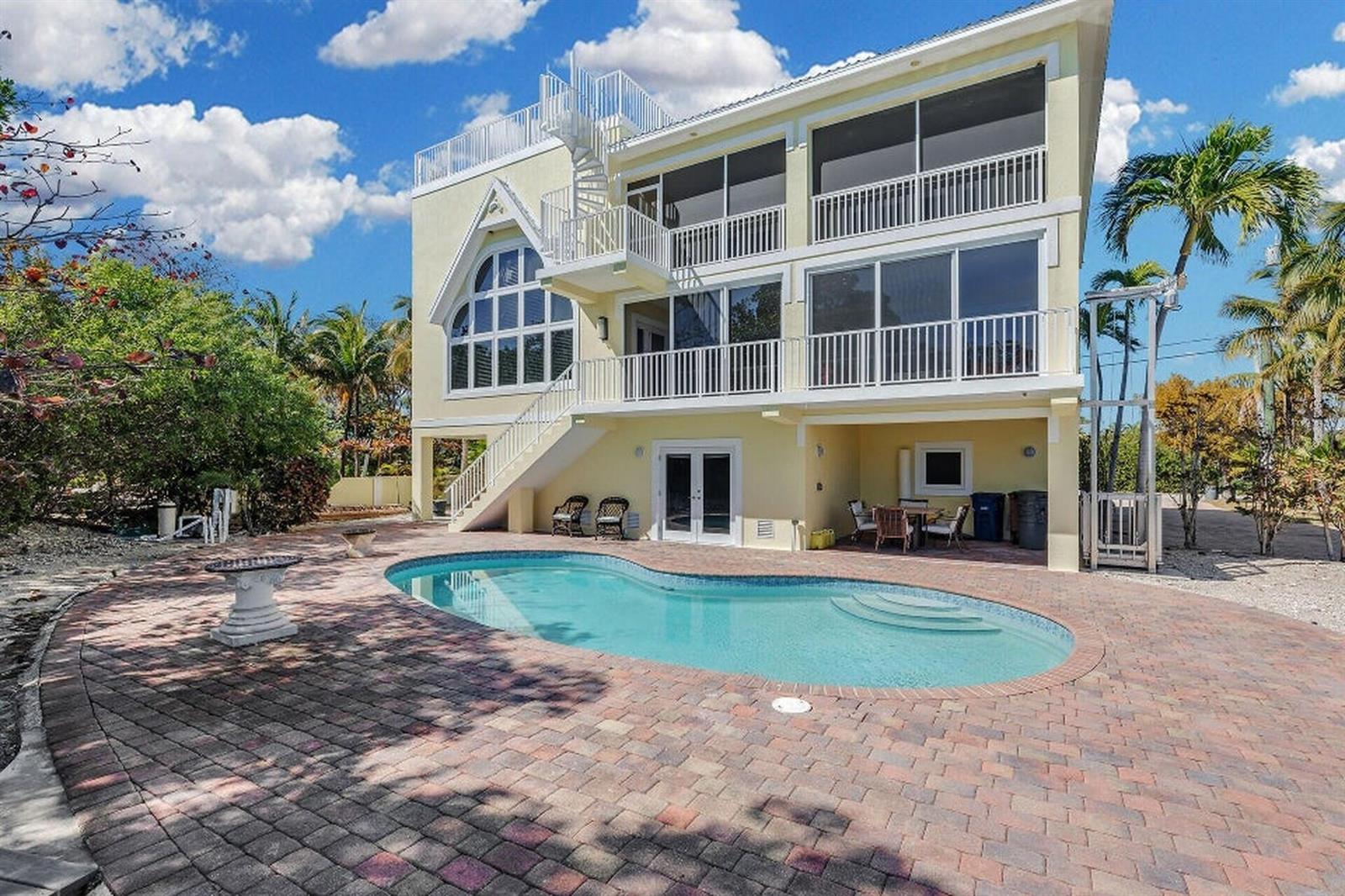 A three-story yellow house with a swimming pool, spiral staircase, and large screened-in balconies — 205 Stirrup Key Boulevard, Marathon FL 33050, MARATHON, FL