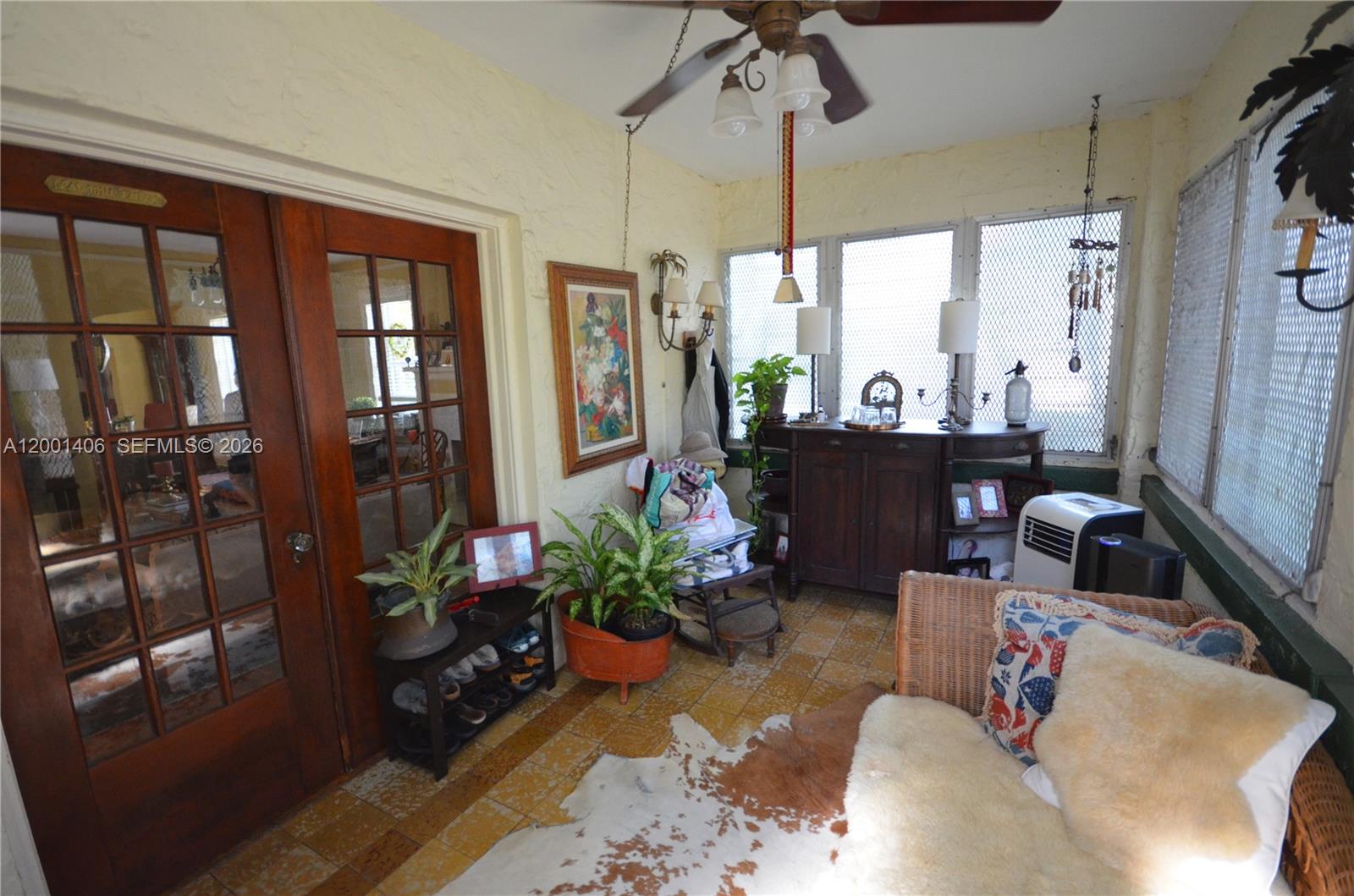A sunroom features tiled floors, a ceiling fan, wicker furniture, and large wooden French doors — 334 NE 26th Ter, Miami FL 33137, MIAMI, FL