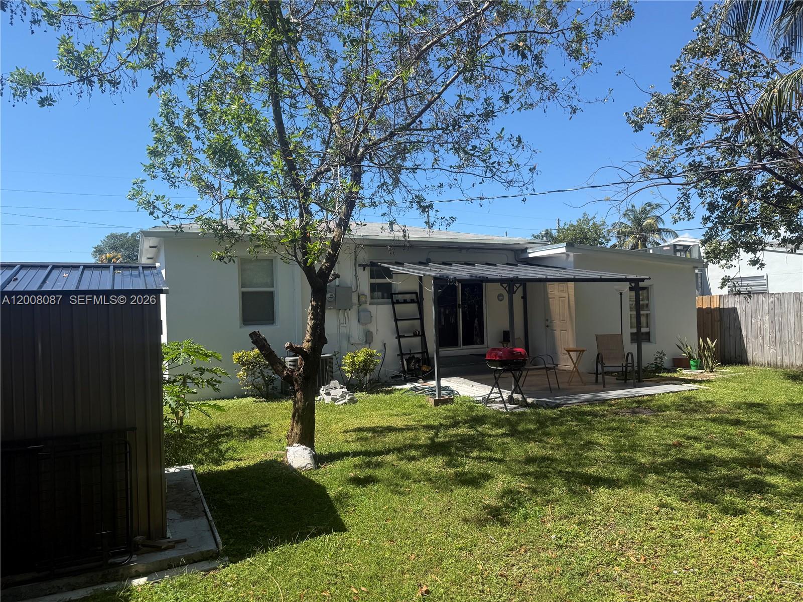 The backyard features a white house with a covered patio, a shed, and a tree — 2323 Cleveland St, Hollywood FL 33020, HOLLYWOOD, FL