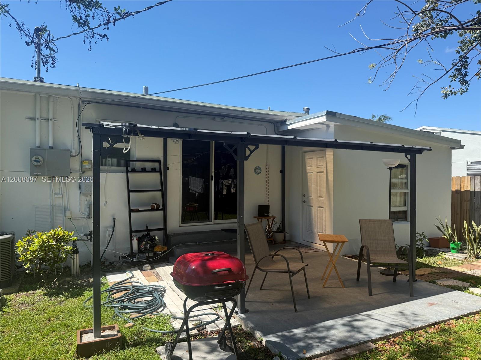 A backyard patio features a metal pergola, a red charcoal grill, and two outdoor chairs — 2323 Cleveland St, Hollywood FL 33020, HOLLYWOOD, FL
