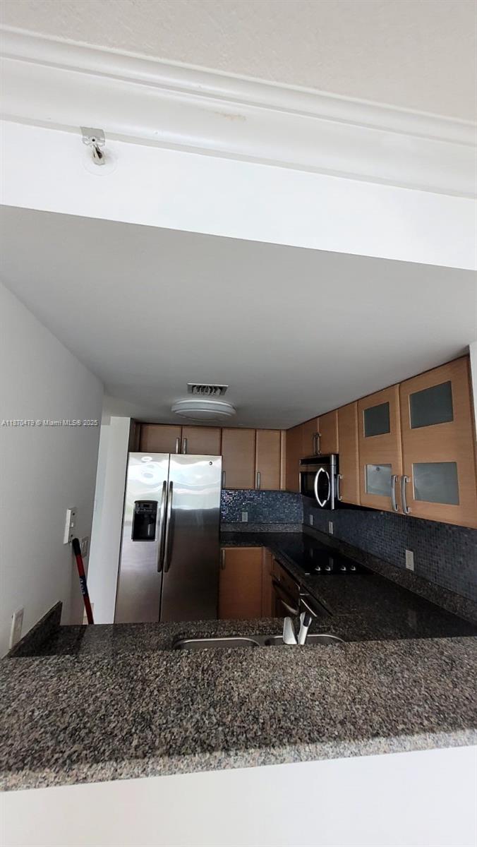 A kitchen features granite countertops, light wood cabinets, stainless steel appliances, and a tiled backsplash — 2101 Brickell Ave # 1109, Miami FL 33129, MIAMI, FL