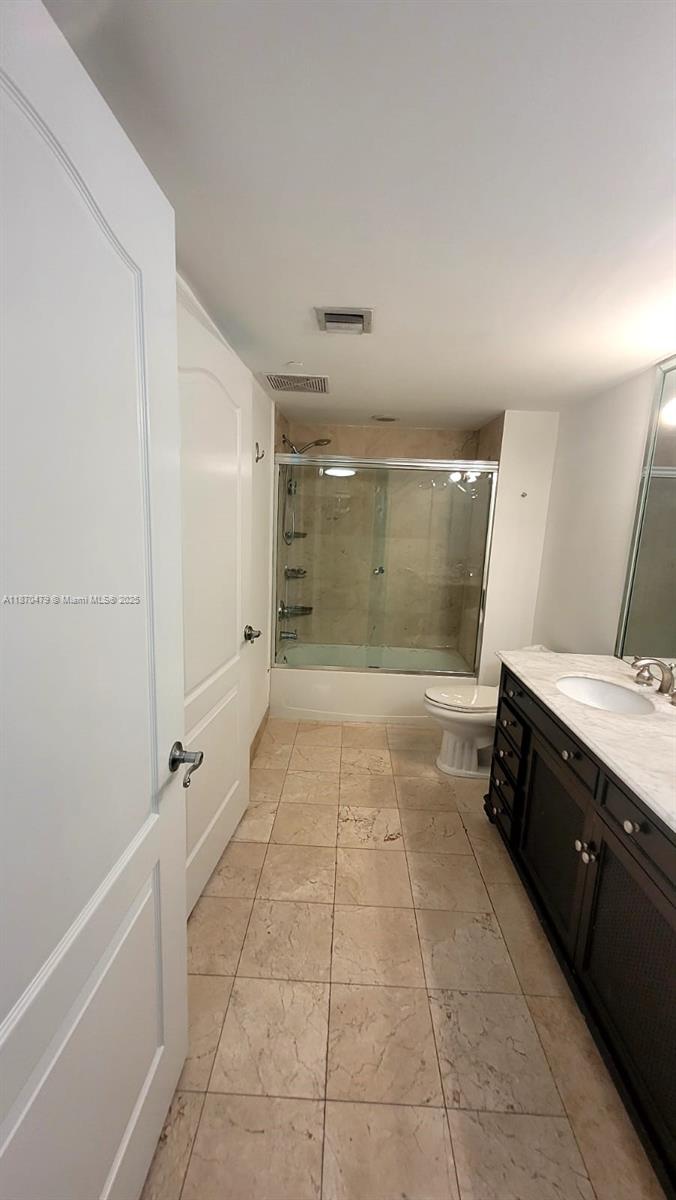 A bathroom features a dark wood vanity, a glass-enclosed shower, and light-colored tile flooring — 2101 Brickell Ave # 1109, Miami FL 33129, MIAMI, FL