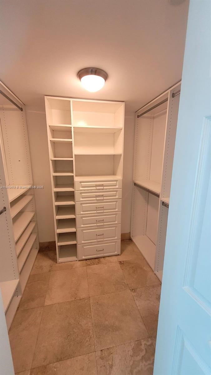A walk-in closet features white shelving, a built-in dresser, and tile flooring — 2101 Brickell Ave # 1109, Miami FL 33129, MIAMI, FL