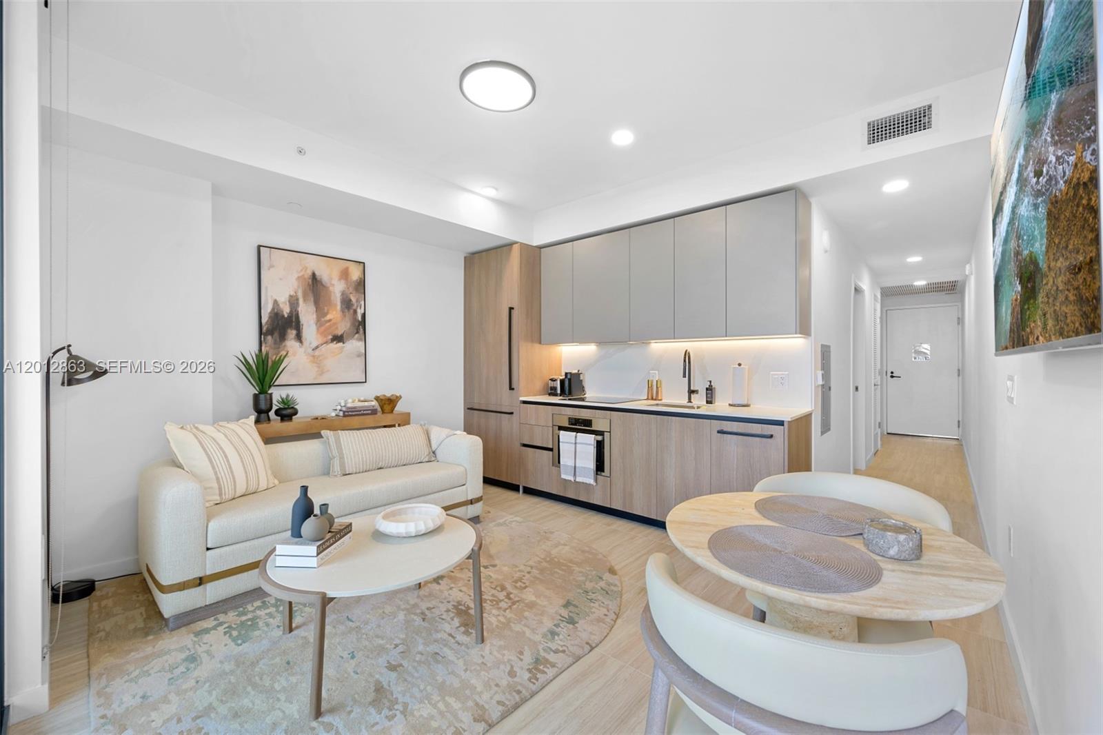 A modern studio apartment features a kitchenette, a sofa, and a small dining table — 580 72nd St # 611, Miami Beach FL 33141, MIAMI BEACH, FL