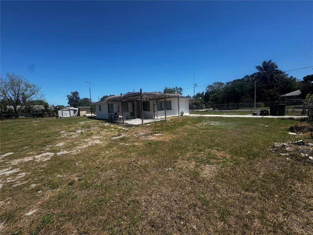 A single-story white house with a covered patio sits on a large, grassy lot — 121 33RD AVENUE E, BRADENTON, FL