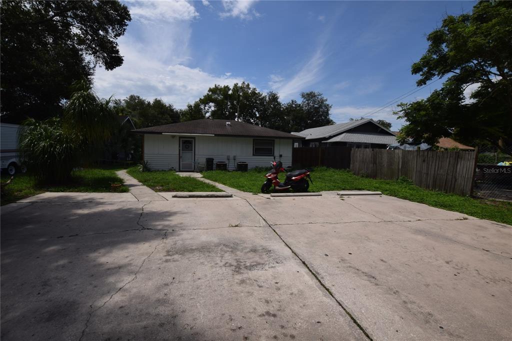 A concrete parking area sits in front of a single-story house with a red scooter — 305 W HANCOCK STREET, LAKELAND, FL