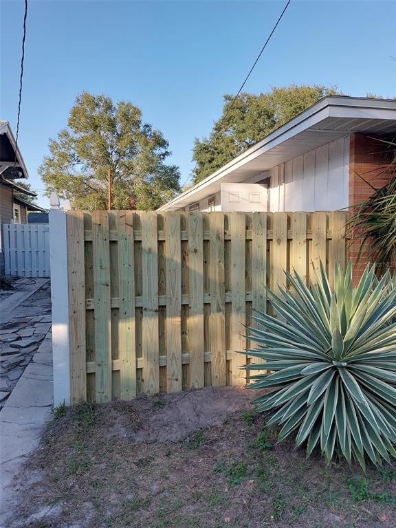 A wooden privacy fence stands in a yard next to a brick and siding house — 305 W HANCOCK STREET, LAKELAND, FL