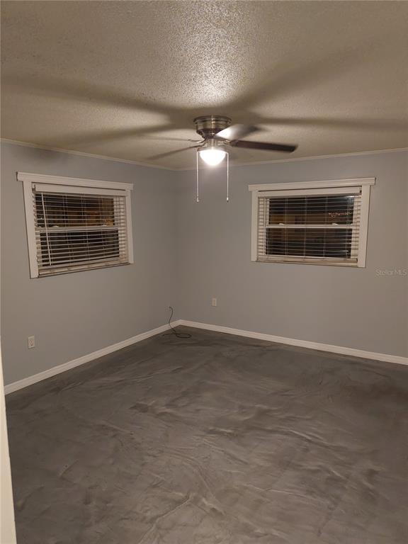 An empty bedroom features light blue walls, white trim, a ceiling fan, and gray flooring — 305 W HANCOCK STREET, LAKELAND, FL