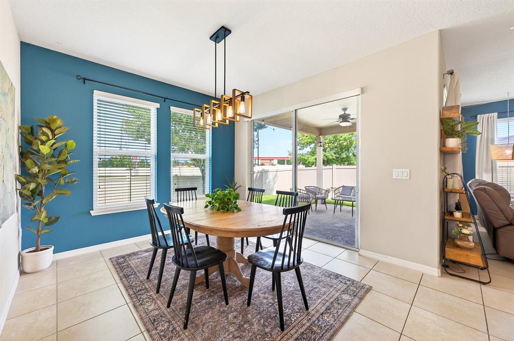 A dining room with a wooden table, black chairs, a blue accent wall, and patio access — 4062 BROOKSHIRE CIRCLE, EUSTIS, FL