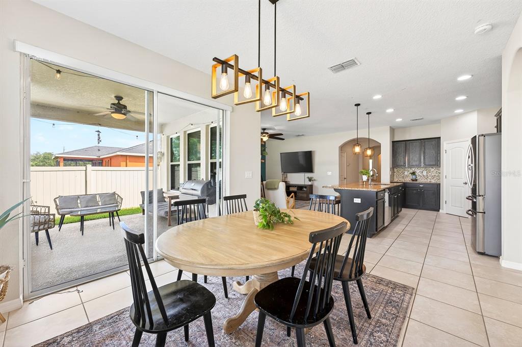 A dining area with a wooden table and black chairs opens to a covered patio — 4062 BROOKSHIRE CIRCLE, EUSTIS, FL