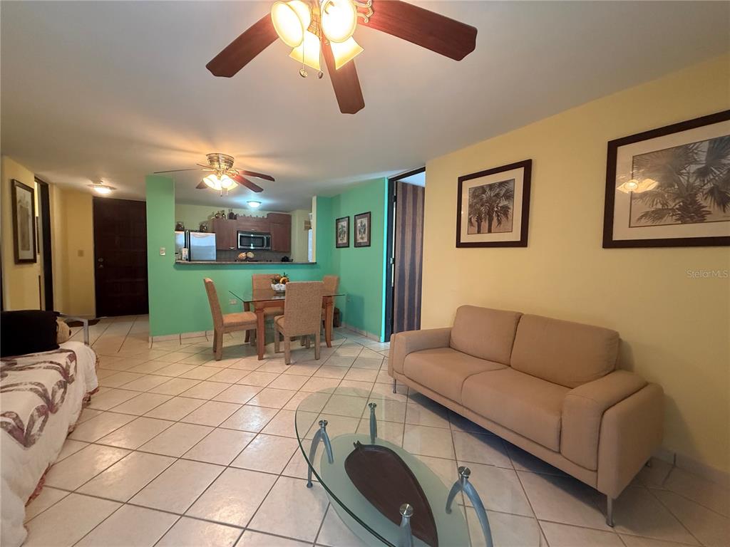 A living room with tile floors, a beige sofa, and a dining area with green walls — 614 NE BEACHSIDE DRIVE UNIT 205, LUQUILLO, PR