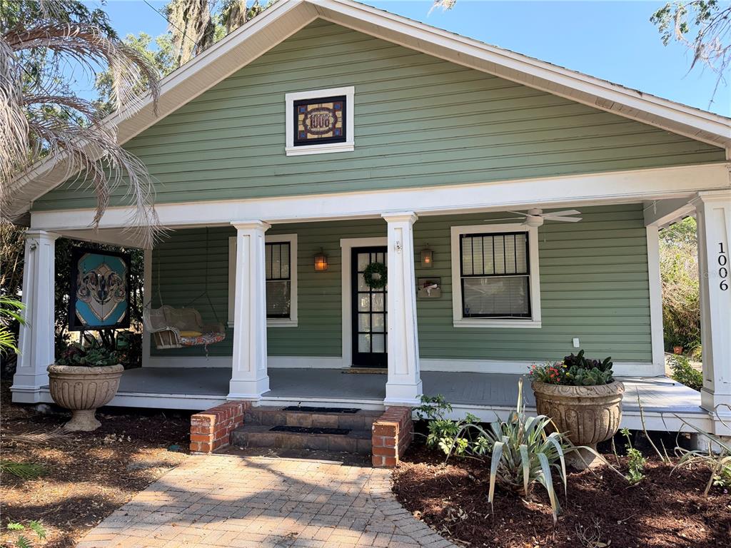 A green house with a front porch, columns, and a brick walkway — 1004 PALMER STREET, ORLANDO, FL