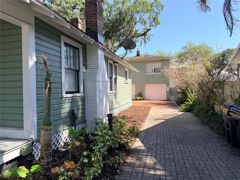 A side view of a green house with a brick chimney and a paved driveway — 1004 PALMER STREET, ORLANDO, FL
