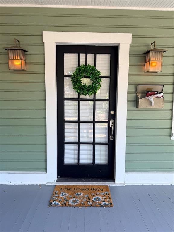 A front porch features a black door with a wreath, two wall lamps, and a doormat — 1004 PALMER STREET, ORLANDO, FL