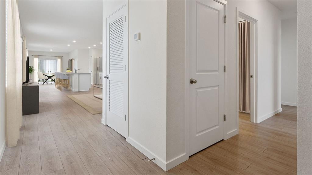 A hallway with light wood flooring leads to an open-concept kitchen and living area — 5162 BLANKET FLOWER STREET, APOPKA, FL