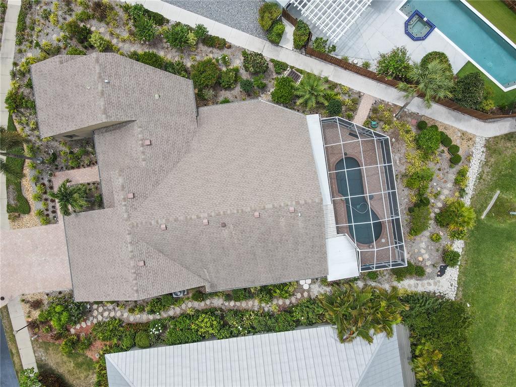 An aerial view shows a house with a shingled roof, a screened-in pool, and landscaping — 2408 89TH STREET NW, BRADENTON, FL