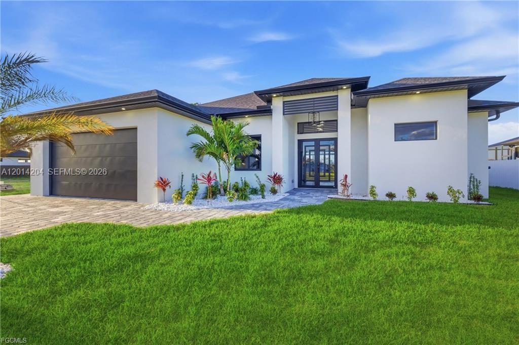 A modern single-story house with a white exterior, dark garage door, and glass front doors — 1031 SW 1st TER, Cape Coral FL 33991, CAPE CORAL, FL