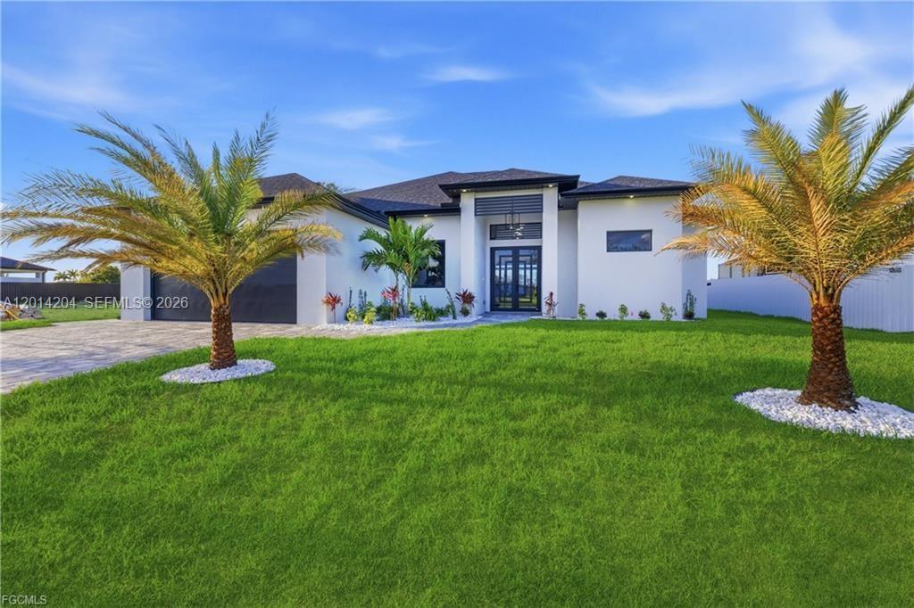 A modern, single-story white house features a dark garage door and two palm trees — 1031 SW 1st TER, Cape Coral FL 33991, CAPE CORAL, FL