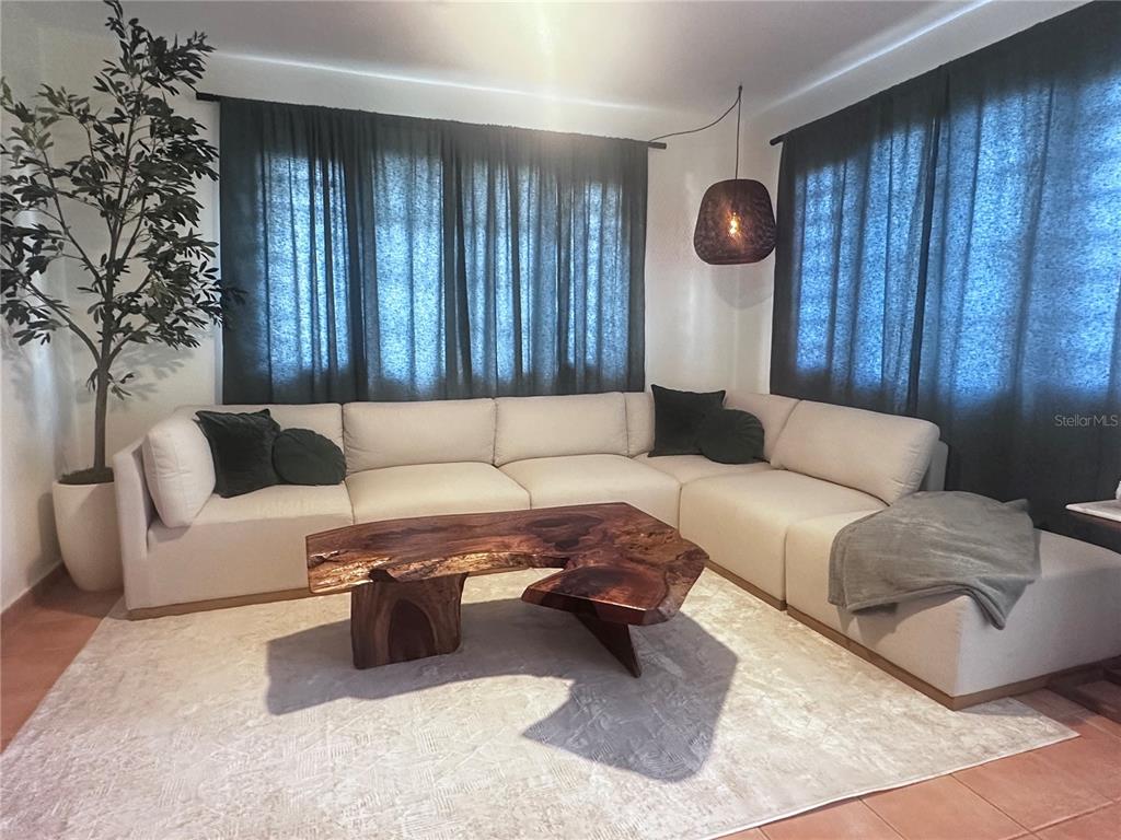 A living room features a large beige sectional sofa, a live-edge wood coffee table, and curtains — Carr 115 Km 17 PUNTA DEL MAR D12, RINCON, PR