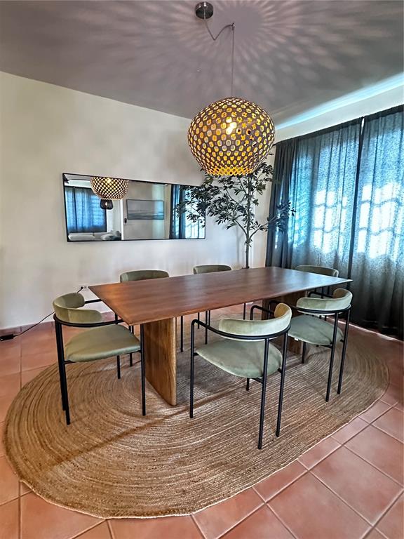 A dining room features a wooden table, green chairs, a woven pendant light, and a rug — Carr 115 Km 17 PUNTA DEL MAR D12, RINCON, PR