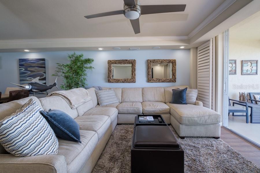 A living room features a large beige sectional sofa, a coffee table, and two mirrors — 4325 GULF OF MEXICO DRIVE UNIT 507, LONGBOAT KEY, FL